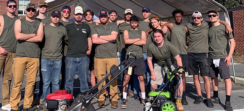 Alpha Gamma Rho Members grouped behind Lawnmowers at the University of Delware